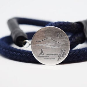 marinblått armband med silverbricka mot vit bakgrund