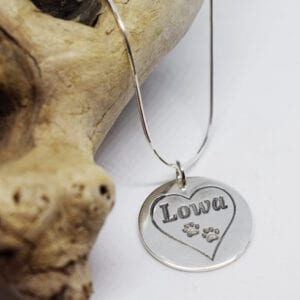 silverhalsband med hjärta och tassar med en trädgren