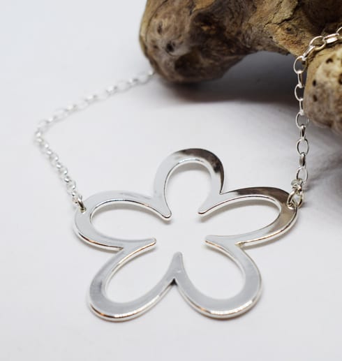 altiflower-2.jpg silverhalsband i form av en blomma på vit bakgrund med trädgren