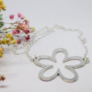 silverhalsband i form av en stor blomma på vit bakgrund med små blommor i rosa och gult