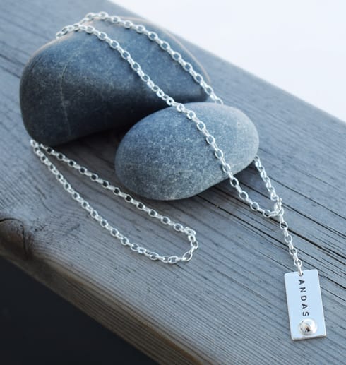 andashalsarm-2.jpg Halsband med texten ANDAS över stenar på trä utomhus