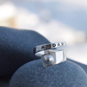 silverring med texten ANDAS på grå stenar utomhus
