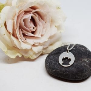 silverhalsband med en ängel på en grå sten med en rosa ros bredvid