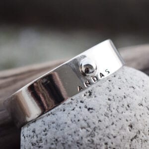 silverarmband med texten ANDAS på sten utomhus