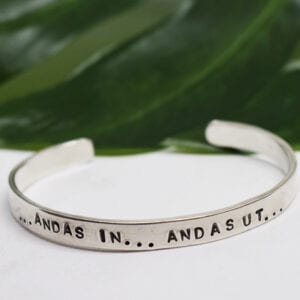 silverarmband med texten andas in andas ut med grönt blad i bakgrunden