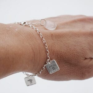 silverarmband med brickor på handled utomhus