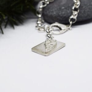 silverarmband med bricka på grå sten bakom