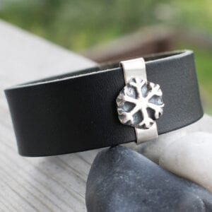 läderarmband med snöflinga i silver på stenar utomhus