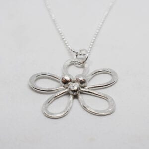 silverhalsband i form av en blomma på vit bakgrund