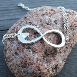 evighetssymbol i silver i form av ett armband på en röd sten
