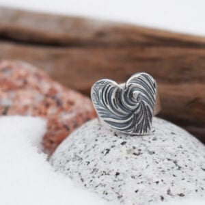 silverring med mösntrat hjärta på stenar med trä och snö utomhus