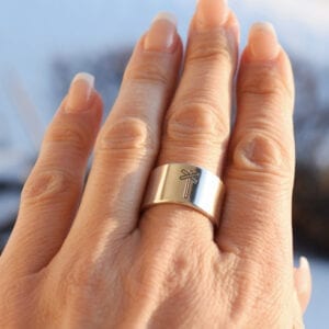 bred silverring med lekryss på finger utomhus
