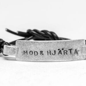 Silverarmband med text och läderband på vit bakgrund