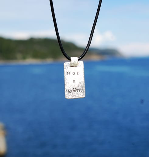 silverhalsband med text hängande utomhus vid havet