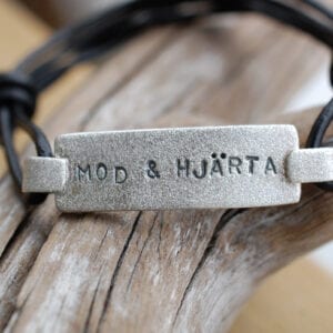 borstat silverarmband med text på trädgren med läderband