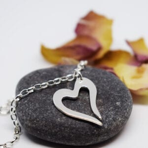 armband med litet silverhjärta på gråsten med rosenblad bakom