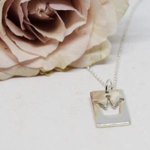 halsband med pinsesskrona mot vit bakgrund och rosa ros