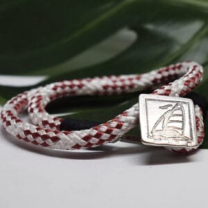 rödvitt armband med silverspänne med segelbåt med grönt blad bakom