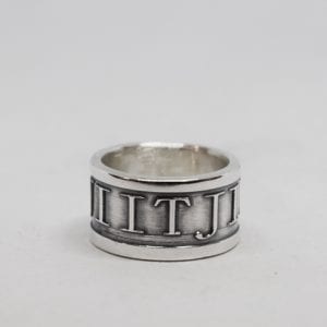 bred silverring med upphöjd text och vit bakgrund