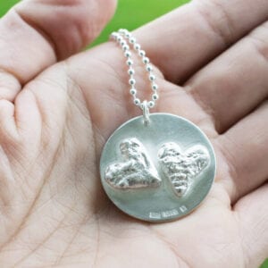 silverhalsband med hjärtan i handflata utomhus