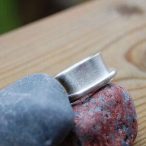 bred silverring på stenar utomhus