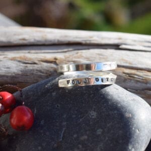 silverring med text på sten med träbit utomhus