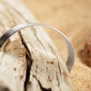 brett silverarmband på trädgren med sand bakom