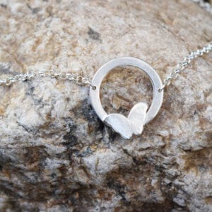 silverhalsband med fjäril utomhus å beige sten