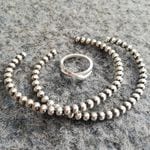 Två silverarmband och en silverring på grå bakgrund