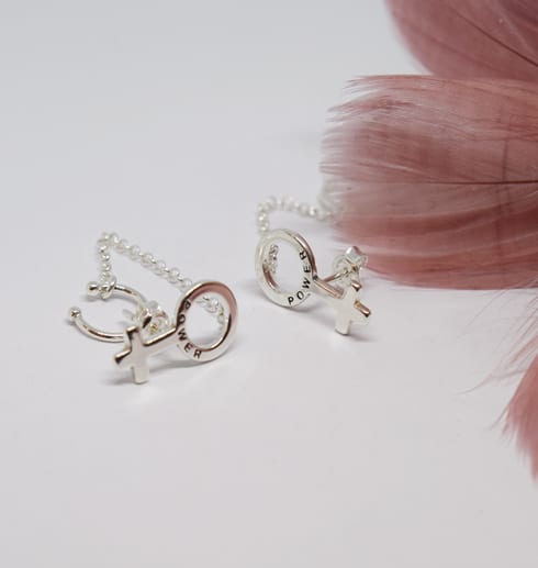 earcuff6 silverörhängen i form av kvinnosymbolenpå vit bakgrund med rosa fjäder bredvid