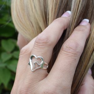 silverring med dubbelhjärta på kvinnas finger utomhus