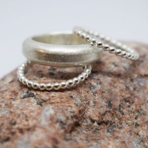 tre ringar i silver på röd sten