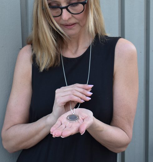 words1 Silverhalsband i lång kedja som kvinna håller i sin hand utomhus