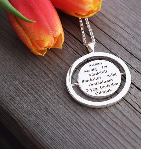 words9 silverhalsband med 10st ord på trä med tulpaner bredvid utomhus