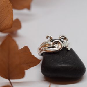 silverring med vågor på svart sten med orange växt bredvid