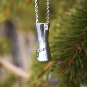 Silverhalsband med text utomhus framför gröna träd